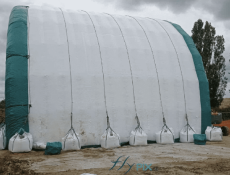 The very large military inflatable sheds must be well ballasted on the ground. Here we see 8 sand-filled ballast bags positioned on the ground at the foot of the side wall of the half-moon inflatable tunnel module, with the guy ropes and metal fixing rings.