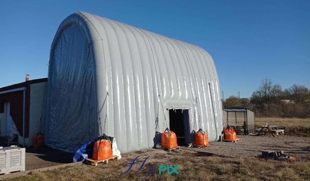 A captive air military inflatable shed hangar, in an inverted U shape, in 0.6 mm double-skin padded PVC envelope, for the maintenance, repair and servicing of military radar equipment or vehicles.