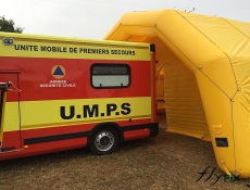 View of the main door with an awn that provides protection from rain and weather while unloading a stretcher from the first aid vehicle through the rear doors, allowing quick and easy entry into the treatment room of the military inflatable tent.