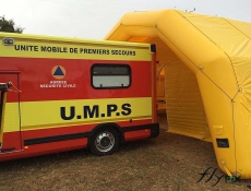 View of the main door with an awn that provides protection from rain and weather while unloading a stretcher from the first aid vehicle through the rear doors, allowing quick and easy entry into the treatment room of the military inflatable tent.