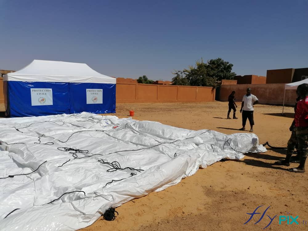 Technicians are placing the inflatable PMA tent on the ground, which will then be inflated for a pressure test.