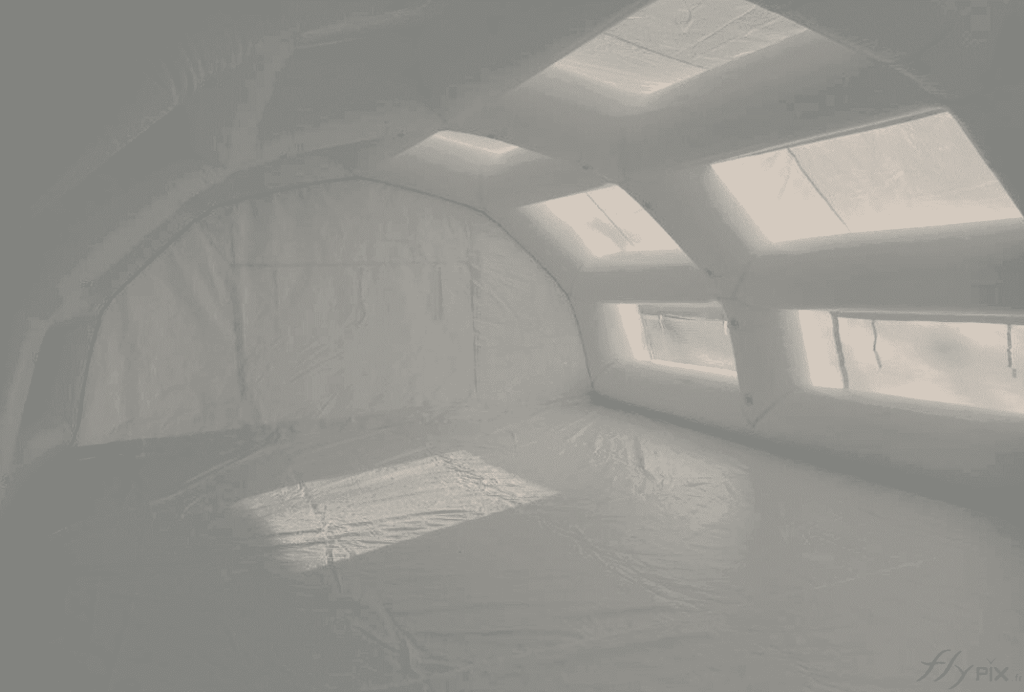 An interior view of the inflatable first aid station shelter manufactured for the SAMU (Emergency Medical Service) of the Evreux Hospital Center , providing a very large space, a very large surface area, and a very large usable work volume for medical staff and doctors. A PVC-coated tarpaulin floor creates a clean, hygienic, and moisture-free first aid area. The tarpaulin also provides better thermal insulation and protects against moisture rising from the ground. The usable interior space is ideal for accommodating a significant number of patients and can be furnished with folding medical beds, desks, etc. – Copyright Vivien LAÏLLE / FlyPix – All rights reserved, reproduction prohibited.