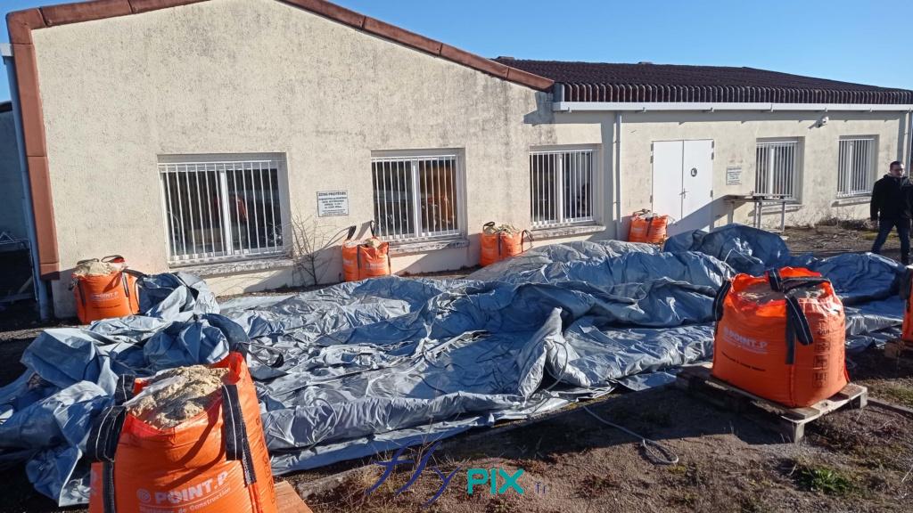 The technicians are setting up the inflatable shelter on the ground, and the ballast bags for the guy lines. - All rights reserved, copyrights FLYPIX. Positioning of the ballast bags for guying the inflatable tent, here big bags filled with sand. The PVC envelope is fully deployed on the ground. – All rights reserved, copyright FLYPIX.