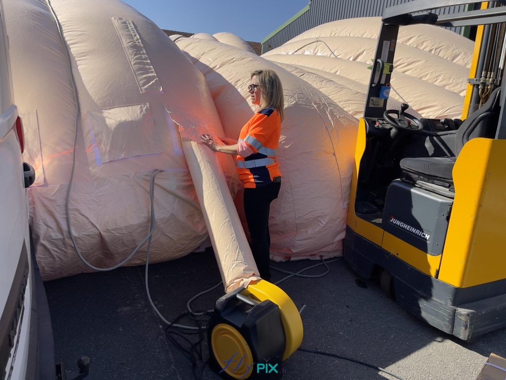 In this photo, we see a technician/operator inflating a second module of the inflatable hangar, using a turbine and an air sleeve. - Copyright: Vivien LAÏLLE/FLYPIX, all rights reserved. In this photo, we see a technician/operator inflating a second module of the inflatable hangar, using a turbine and an air sleeve. – Copyright: Vivien LAÏLLE/FLYPIX, all rights reserved.
