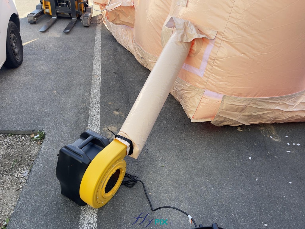 A detailed view of the turbine and the air sleeve that continuously pumps air into the inflatable structure. This electric turbine has a power output of approximately 2500 W. Ideally, several turbines are needed to inflate the inflatable structure. - Copyright: Vivien LAÏLLE/FLYPIX, all rights reserved. A detailed view of the turbine and the air sleeve that continuously pumps air into the inflatable structure. This electric turbine has a power output of approximately 2500 W. Ideally, several turbines are needed to inflate the inflatable structure. – Copyright: Vivien LAÏLLE/FLYPIX, all rights reserved.