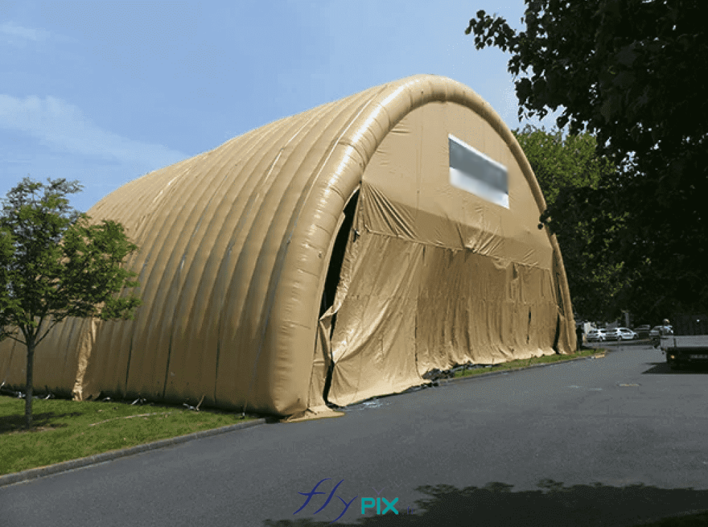 NEXTER: a large inflatable military hangar, shaped like a half-moon tunnel, entirely made of double-skinned, padded PVC, providing a large volume, a large usable area, and a significant height. This type of inflatable military hangar can be deployed rapidly and provides military personnel, soldiers, officers, and other military personnel with a storage and maintenance facility for military vehicles or equipment for operational purposes in the event of armed conflict. – All rights reserved, copyright FLYPIX.