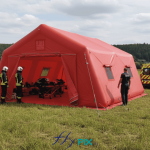 A simulation view showing the deployment of a 37 m² PMA tent, a captive air inflatable structure inflated with an electric pump. Deployment in a rural area. This inflatable shelter has a 0.6 mm single-layer PVC shell for the airtight inflatable tube frames, and a 0.45 mm single-layer PVC shell for the walls and roof. This inflatable tent is easy to set up and deploy, and when folded, it takes up very little space in the intervention vehicle. A removable groundsheet allows for deployment on a clean and dry surface. – This image was AI-generated using GEMINI, based on 3D model views of the final artwork created by our graphic designer and approved by the client, as well as photos and real-life shots of certain details of the inflatable tent, taken directly in our manufacturing workshop. Media partially generated by AI and verified by an agent. – Copyright Vivien LAÏLLE/FlyPix, all rights reserved, reproduction prohibited.