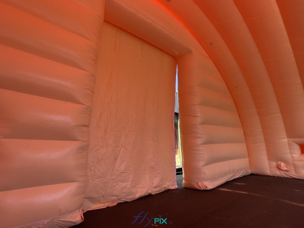 This is a large, wide gable door, a photo taken from the inside, at the level of the front gable module of the inflatable hangar. The large tarpaulin is foldable and closes with wide Velcro strips. - Copyright: Vivien LAÏLLE/FLYPIX, all rights reserved. This is a large, wide gable door, a photo taken from the inside, at the level of the front gable module of the inflatable hangar. The large tarpaulin is foldable and closes with wide Velcro strips. – Copyright: Vivien LAÏLLE/FLYPIX, all rights reserved.