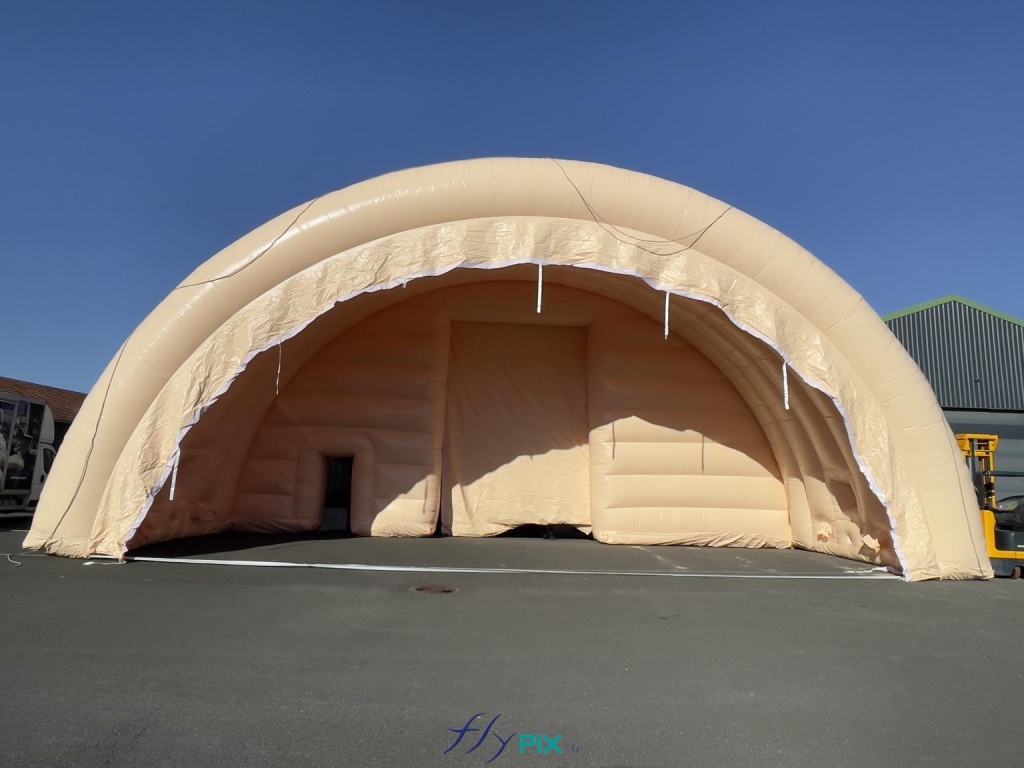 A general view taken from the ground, showing an inflatable tent module in the shape of a half-moon tunnel. This shape is very stable and robust because it provides good natural buttresses, with a keystone, and walls that efficiently distribute the loads of the inflatable structure to the ground. Just like cathedrals. - Copyright: Vivien LAÏLLE/FLYPIX, all rights reserved. A general view taken from the ground, showing an inflatable tent module in the shape of a half-moon tunnel. This shape is very stable and robust because it provides good natural buttresses, with a keystone, and walls that effectively distribute the loads of the inflatable structure to the ground. Just like cathedrals. – Copyright: Vivien LAÏLLE/FLYPIX, all rights reserved.