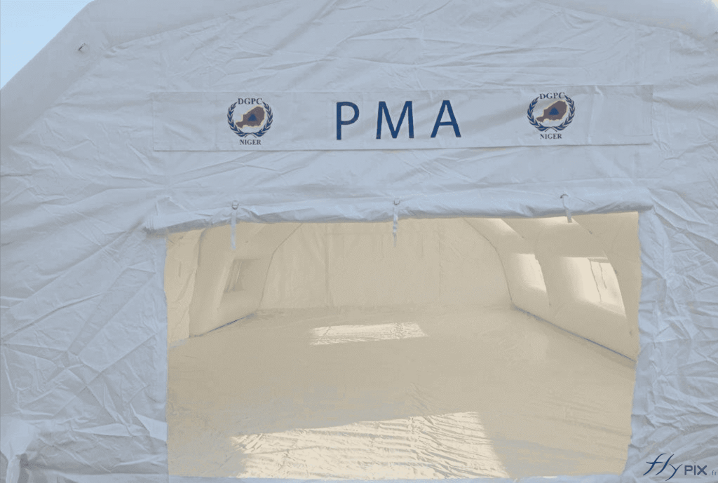 Above the door, there's a removable banner printed with the logo. It's a printed tarpaulin attached to the inflatable tent's outer shell with Velcro strips. The door can be raised and folded away. Extending from it, inside, the removable groundsheet is visible.