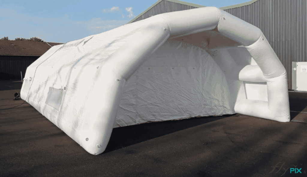 View of the front of the PMA inflatable shelter: access canopy, wide main access door with a ground flap. Metal rings fixed to the inflatable frame wall are visible, for attaching the guy ropes. – Photo: copyright FlyPix/Vivien LAÏLLE, all rights reserved.