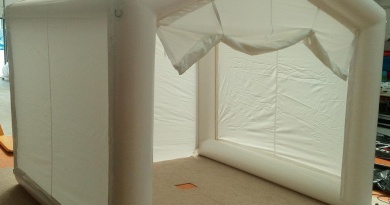 General view of the inflatable tent: the wide gable door at the front is open, the non-return inflation valve is at the bottom left, and on the upper part are metal attachment rings for guy lines, for use in outdoor environments. – All rights reserved, reproduction prohibited. Copyright FlyPix / Vivien LAÏLLE.