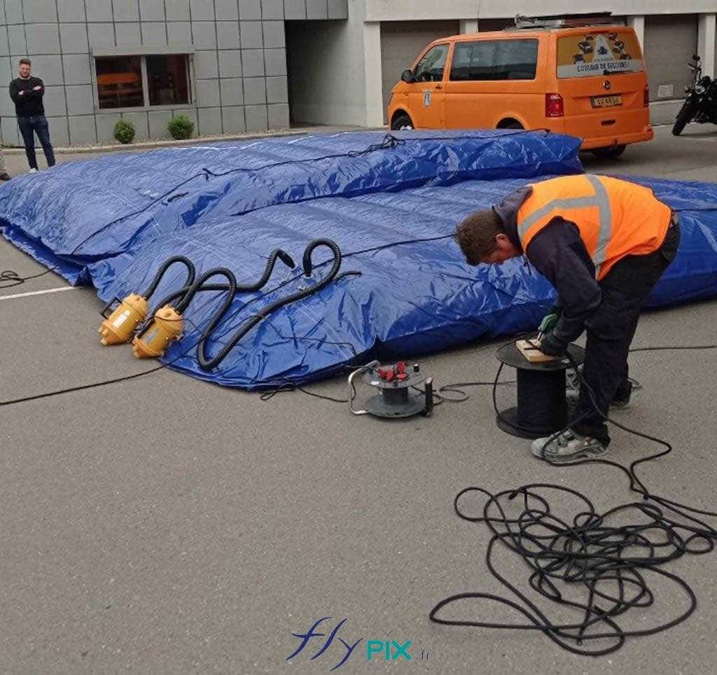 A technician is inflating an inflatable noise-reduction wall using an electric pump. All rights reserved, FLYPIX copyright.