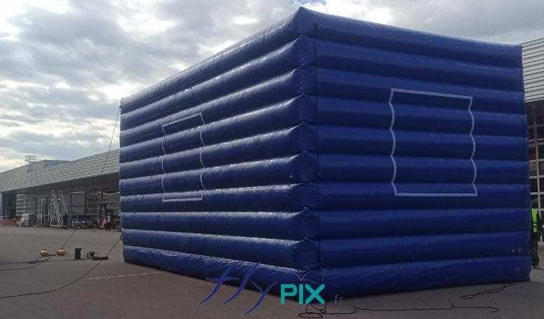General view of a large, dark blue L-shaped wall—a sealed-air inflatable structure made of double-skinned, quilted 0.6 mm PVC. This noise-reduction wall is shown here assembled and installed during an on-site training session. All rights reserved; copyright FLYPIX.